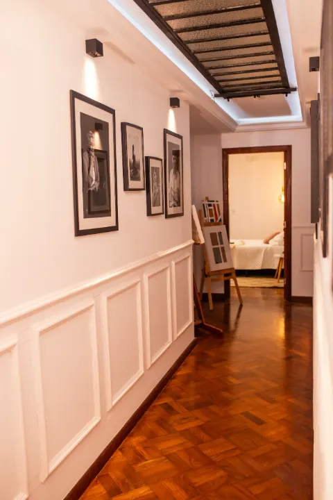 Corredor da galeria com claraboia, quadros e porta para o quarto ao fundo