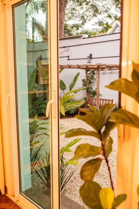 Porta de vidro do escritório aberta para o jardim, com pergolado ao fundo