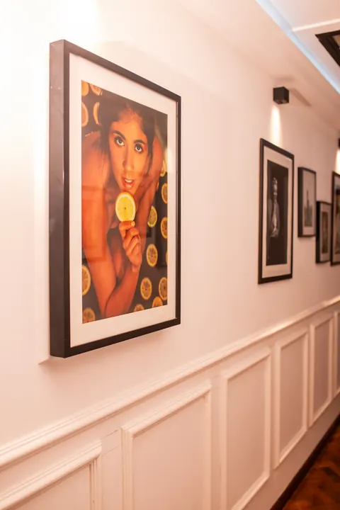 Quadro colorido de retrato feminino na parede da galeria de arte, ao lado de fotografias em preto e branco