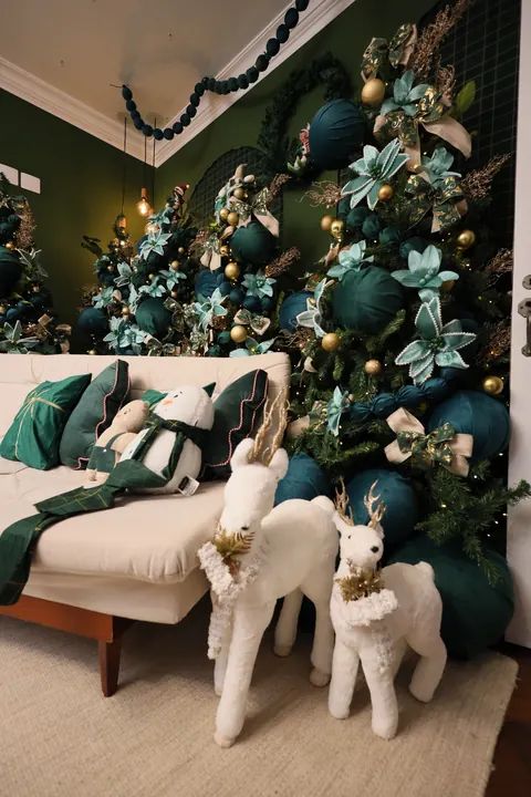 Renas brancas ao lado do sofá branco no cenário de Natal verde do Estúdio Elegance