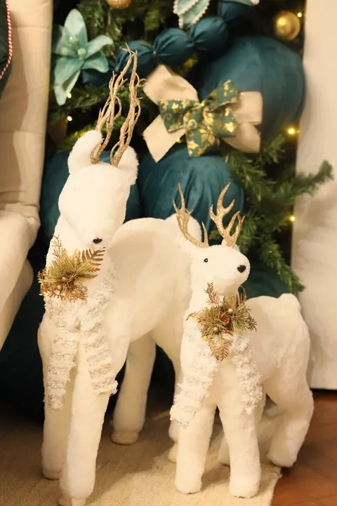 Par de renas brancas decorativas com laço dourado no cenário de Natal do Estúdio Elegance