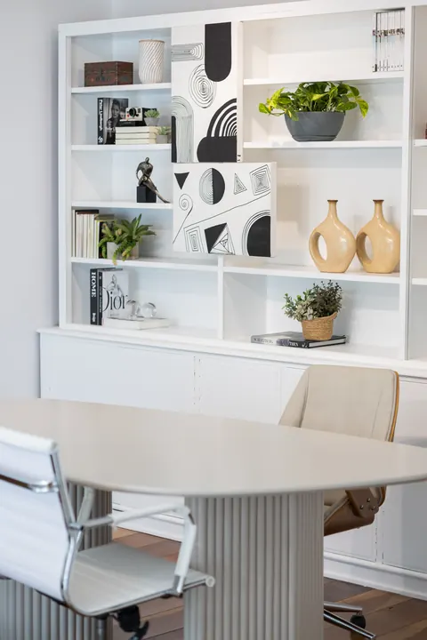 Mesa de reunião branca com cadeiras e estante decorada, cenário corporativo no Loft Lumière