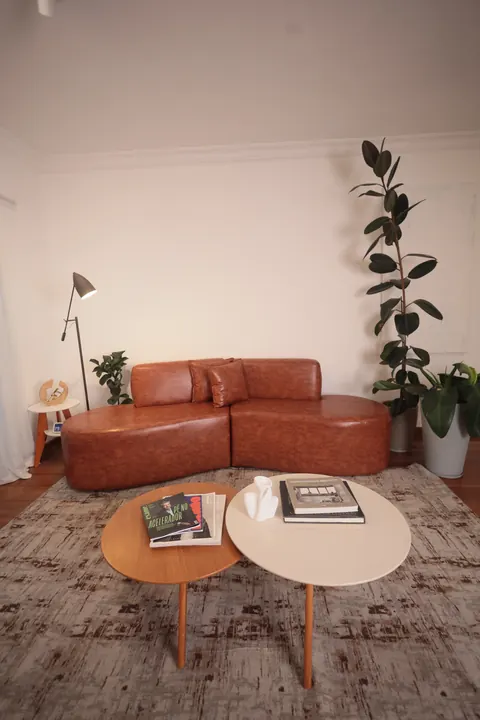 Sofá de couro caramelo com mesas de centro e luminária de piso no Loft Lumière