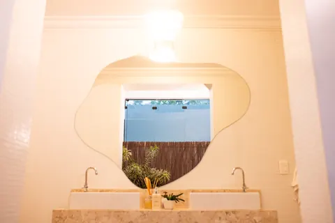 Banheiro com espelho orgânico iluminado e bancada de mármore no Estúdio Majestic