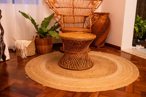 Cadeira pavão de vime com mesa redonda sobre tapete de sisal no Estúdio Majestic