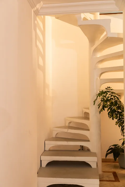 Escada escultural branca, sem corrimão, com planta ao pé