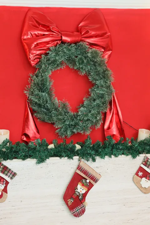 Guirlanda com laço vermelho e meias de Natal sobre a lareira do Loft Oásis