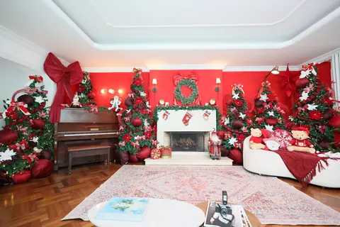 Visão geral do Loft Oásis no Natal: piano, lareira, poltronas e árvores ao longo das paredes vermelhas